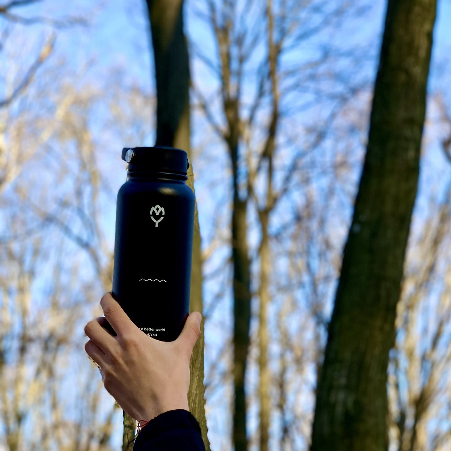 Čierna termoska Panter držaná v ruke vo vzduchu, ukazujúca radosť a osvieženie