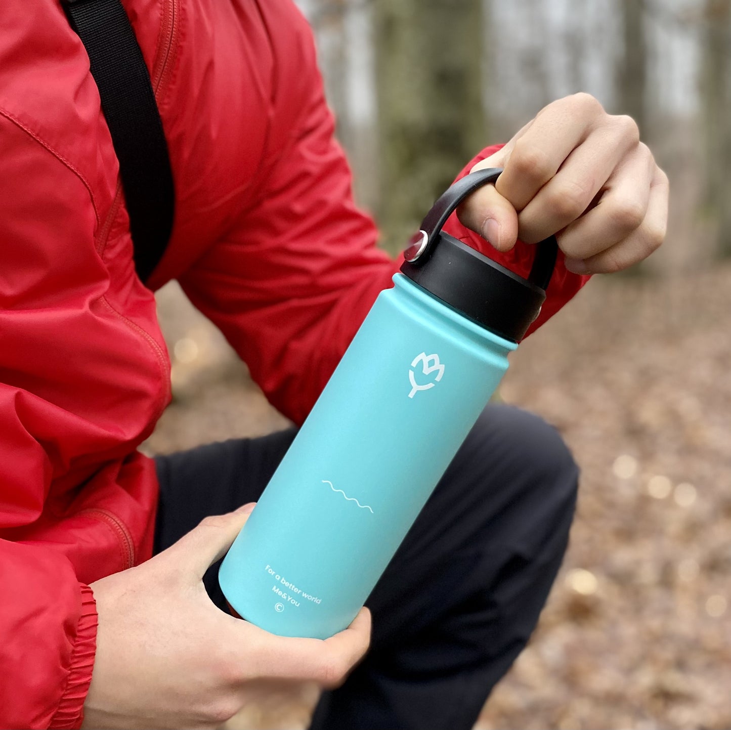 Detská termoska so slamkou 500ML (modrá) držaná oboma rukami mužom v červenom kabáte, bez viditeľnej tváre, zvýraznený dizajn viečka a farba fľaše