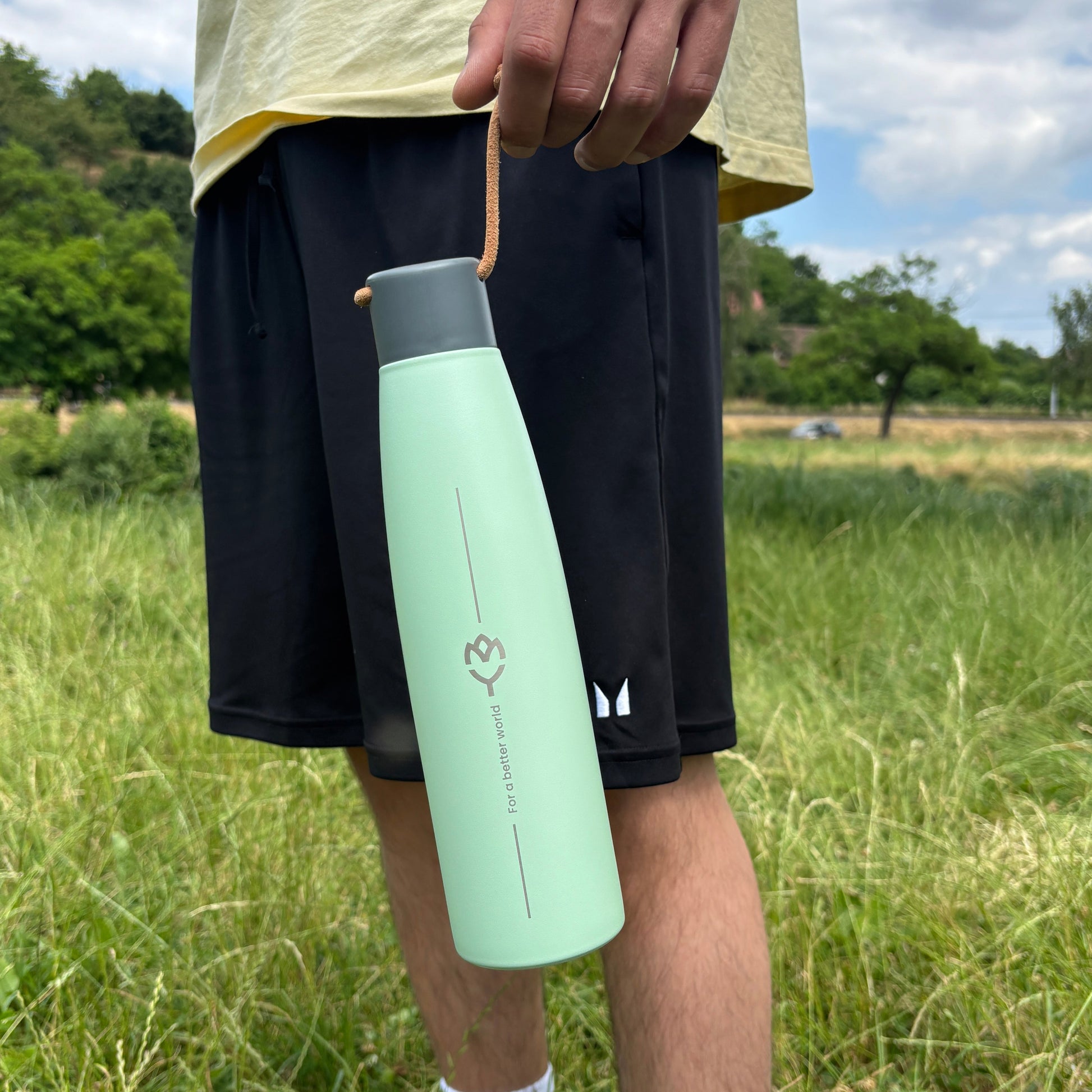 Muž drží termosku Mist jednou rukou pod úrovňou pása – elegantný minimalistický štýl
