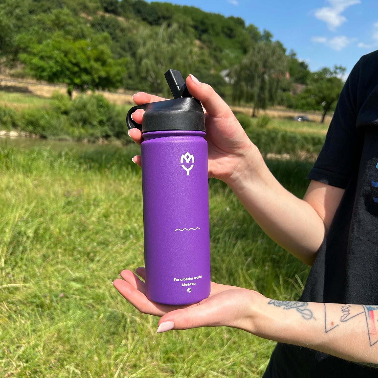 Ženské ruky držiace fialovú termofľašu Gloxie, záber zo spodnej a vrchnej strany zvýrazňujúci jej veľkosť a uzáver

