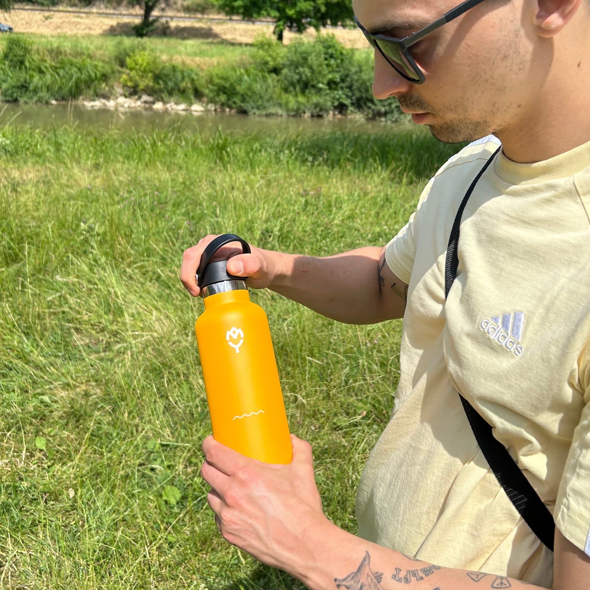Oranžová termoska Mangifera – muž ju drží zhora aj zdola, pohľad na celý dizajn
