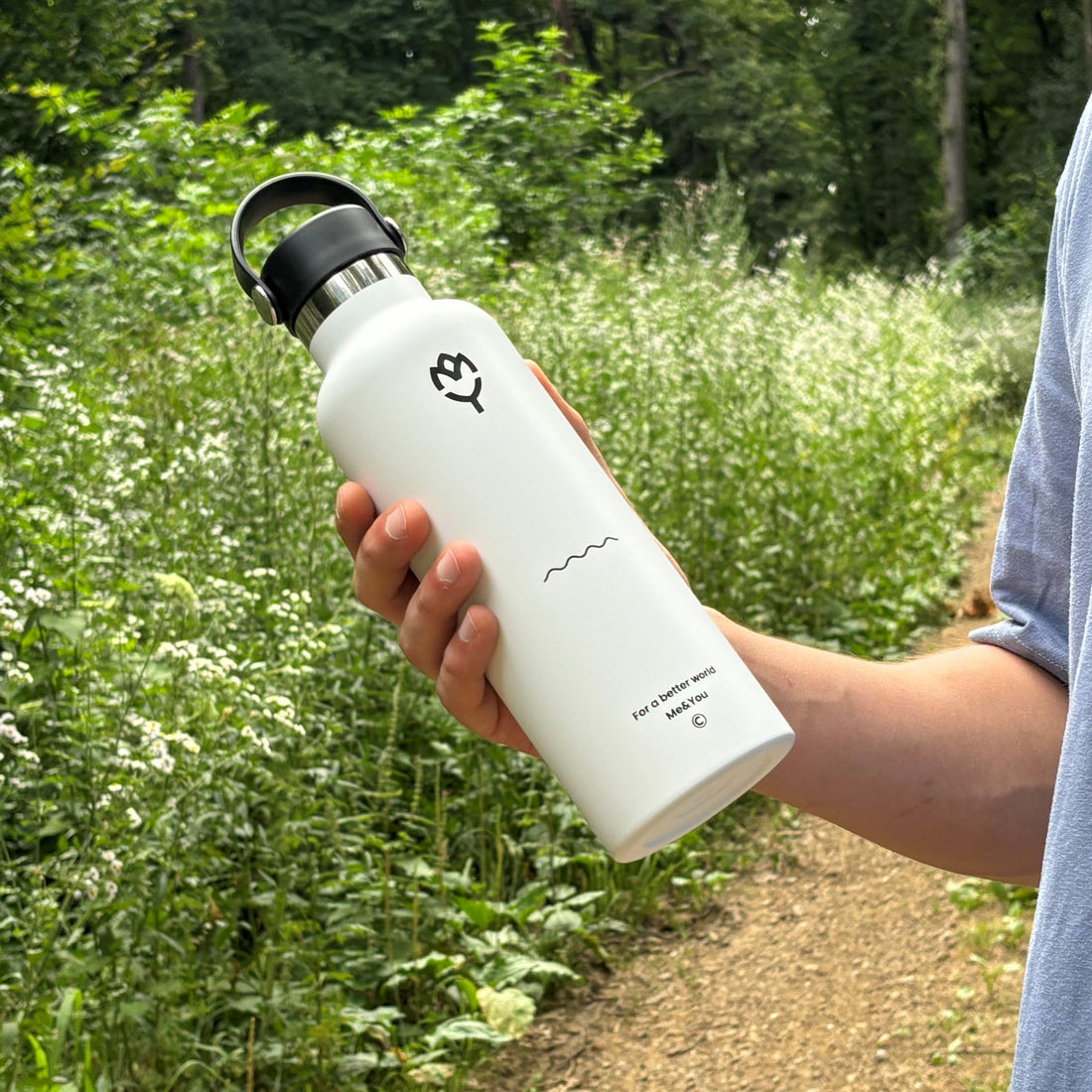 Termoska na vodu Beluga 750ML držaná v ruke, zvýraznený dizajn a farba fľaše, v pozadí les

